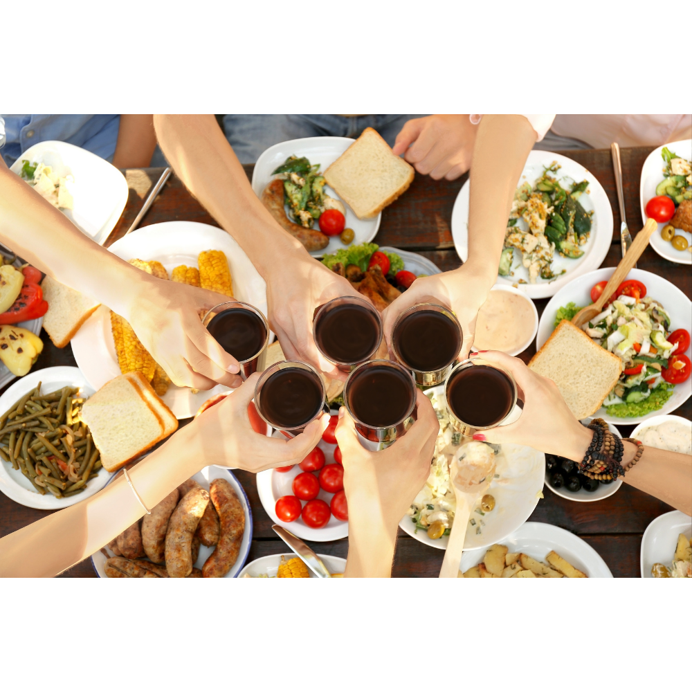 Mains qui se rejoignent autour de verres et de plats lors d’un moment convivial
